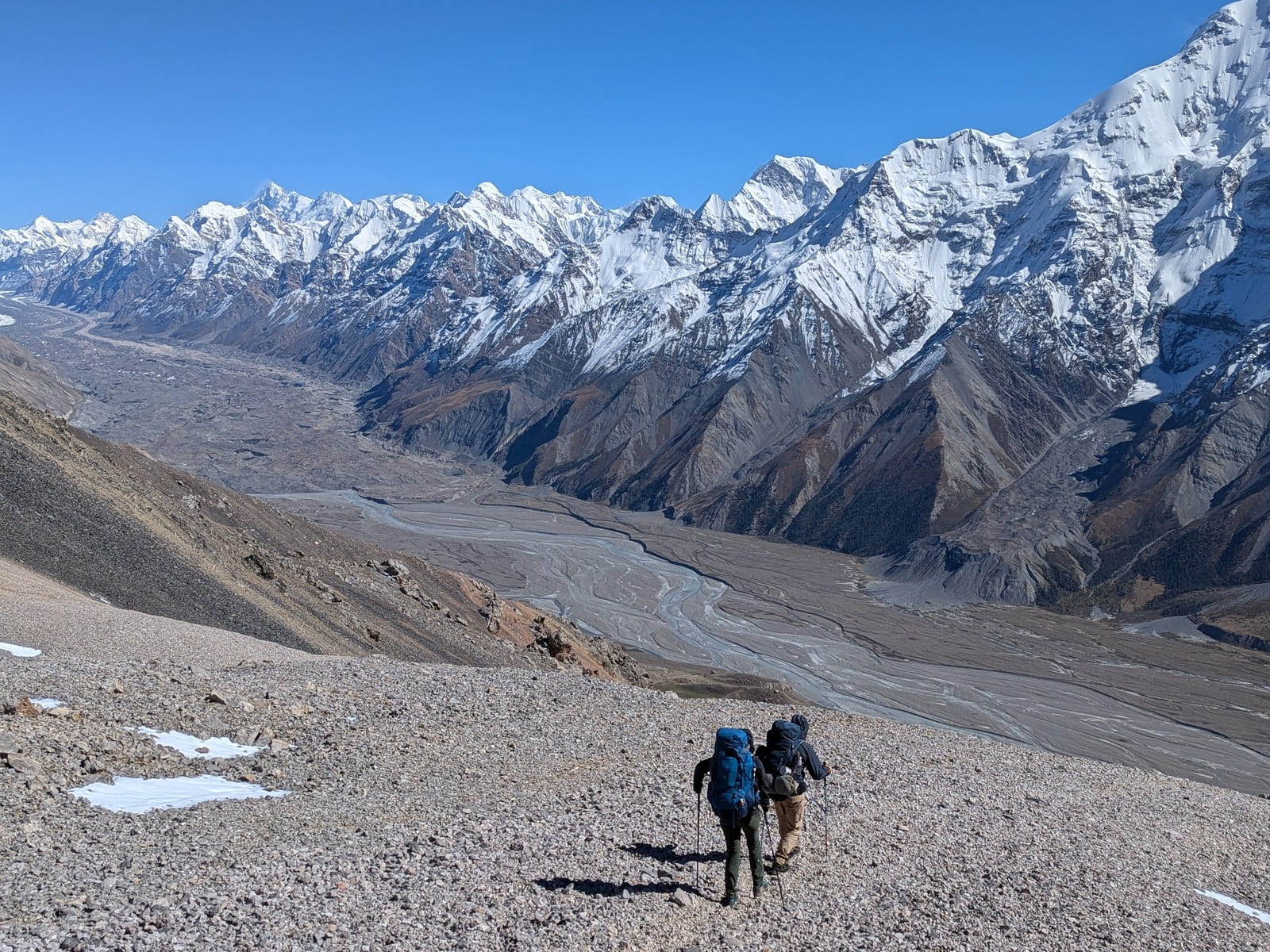 Hikers descending into the Enilchek Valley amidst snow-capped peaks.
