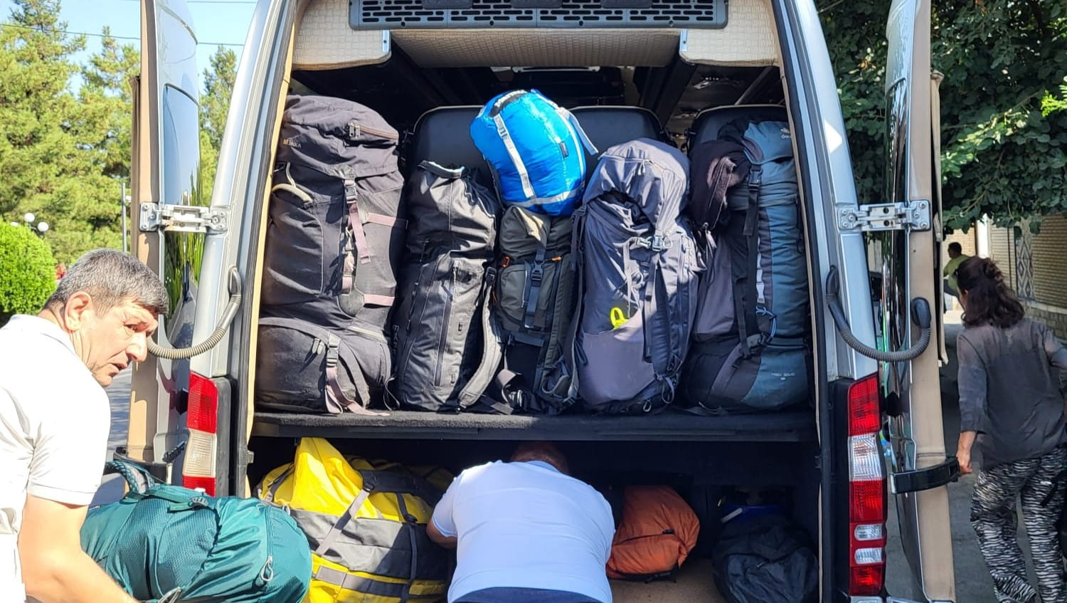 Backpacks stacked in the trunk of a modern marshrutka minibus in Central Asia.