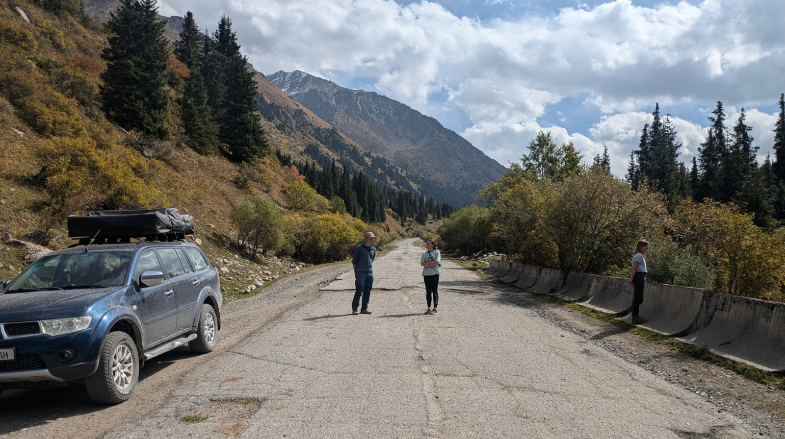 People standing in the middle of a mountainous road in Kyrgyzstan.