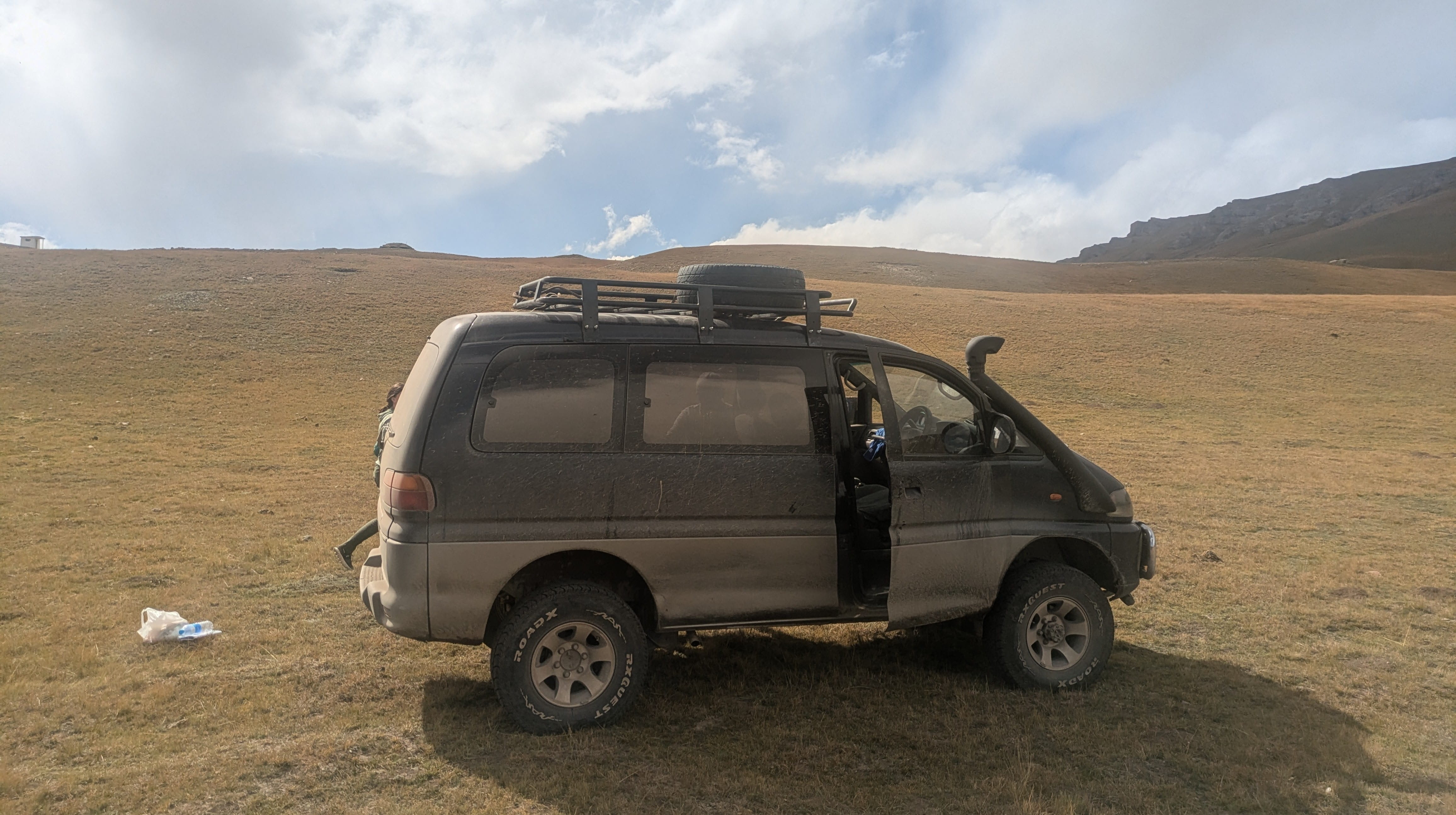 A jeep parked in the yellow hills of Eastern Kyrgyzstan.