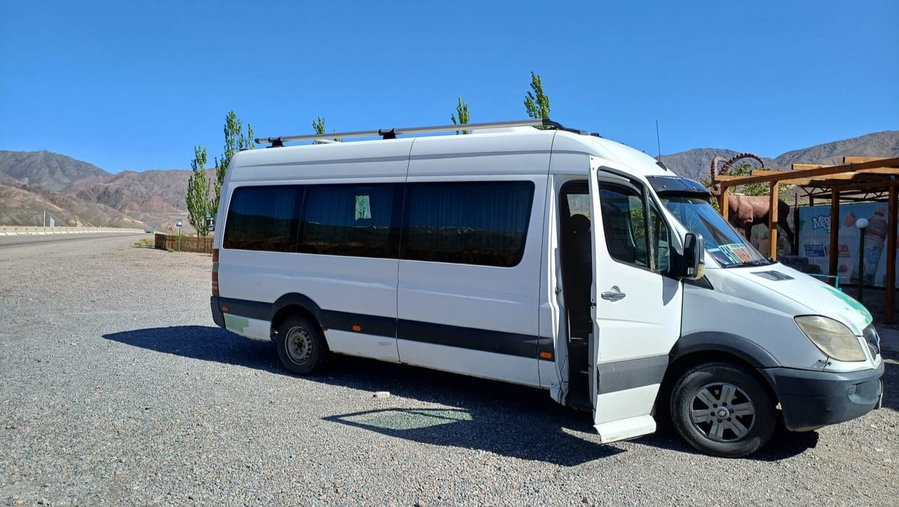 A white sprinter minibus parked in a town in Kyrgyzstan.