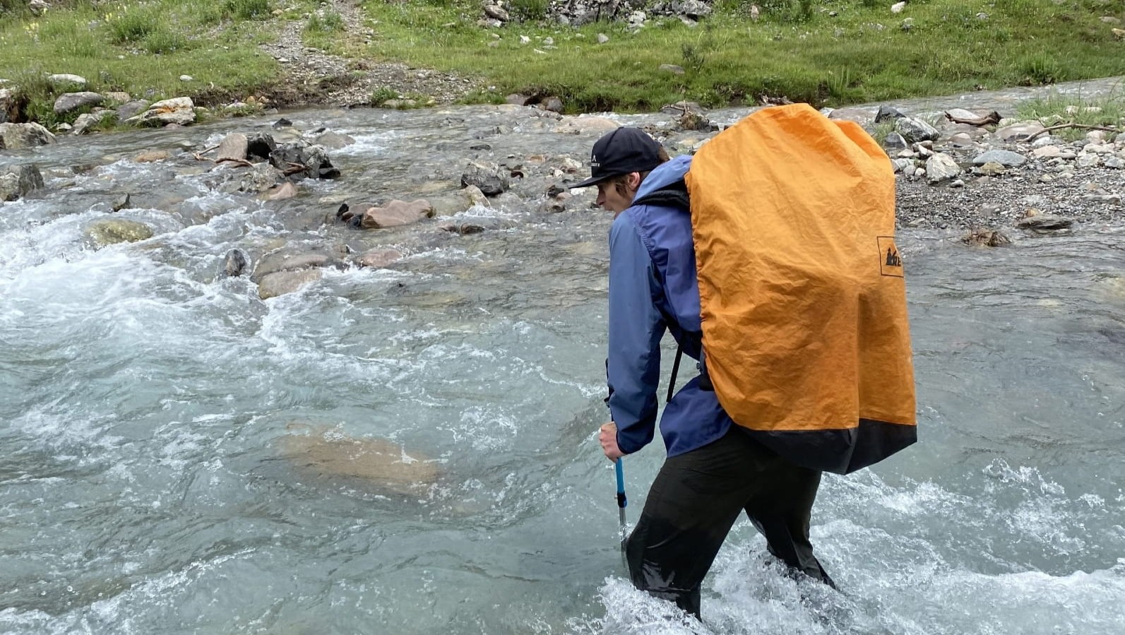 Trekker crossing a fast river in Naryn Region, Kyrgyzstan